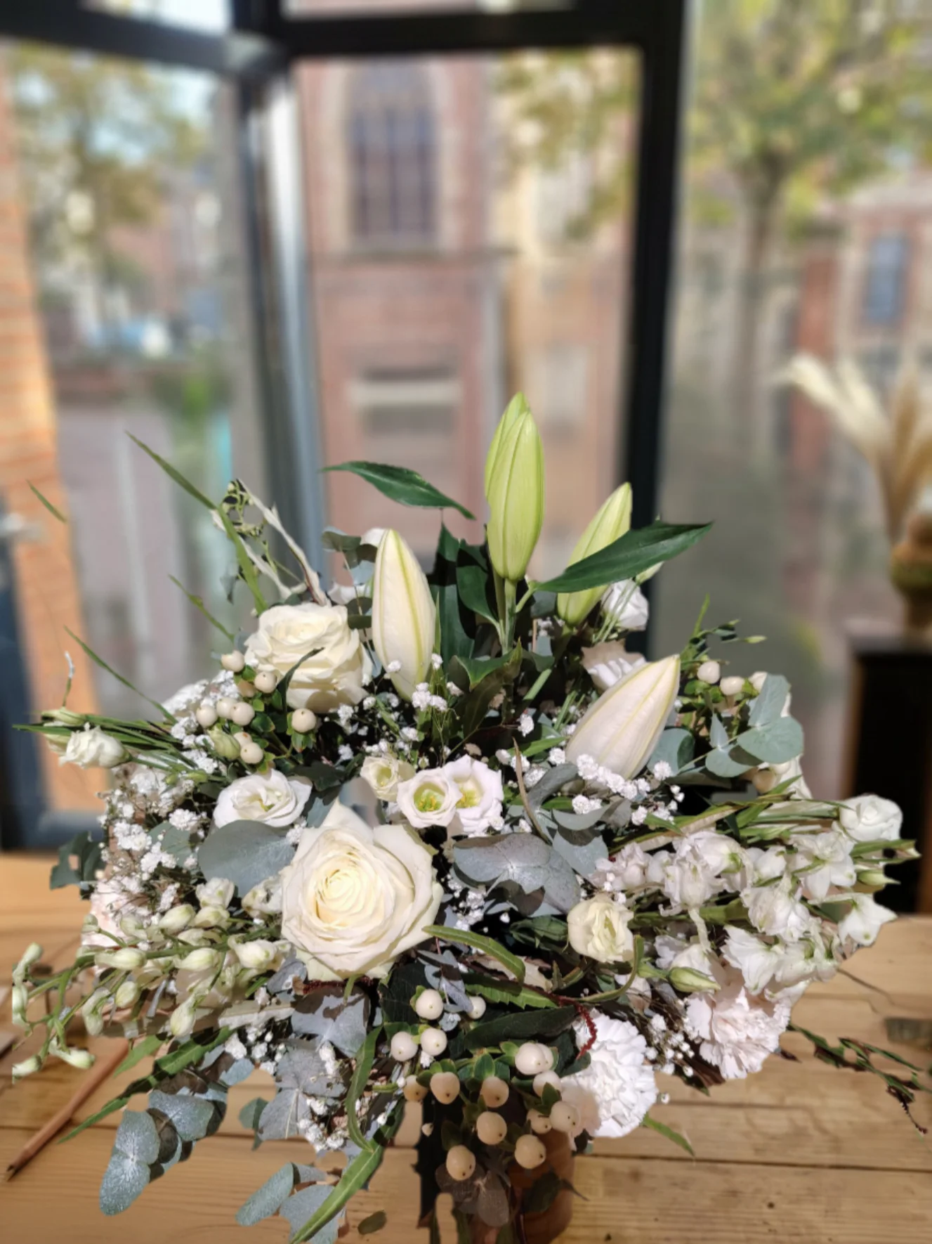 Composition blanche structurée avec de grands boutons floraux, des roses, de petites fleurs et de l'eucalyptus