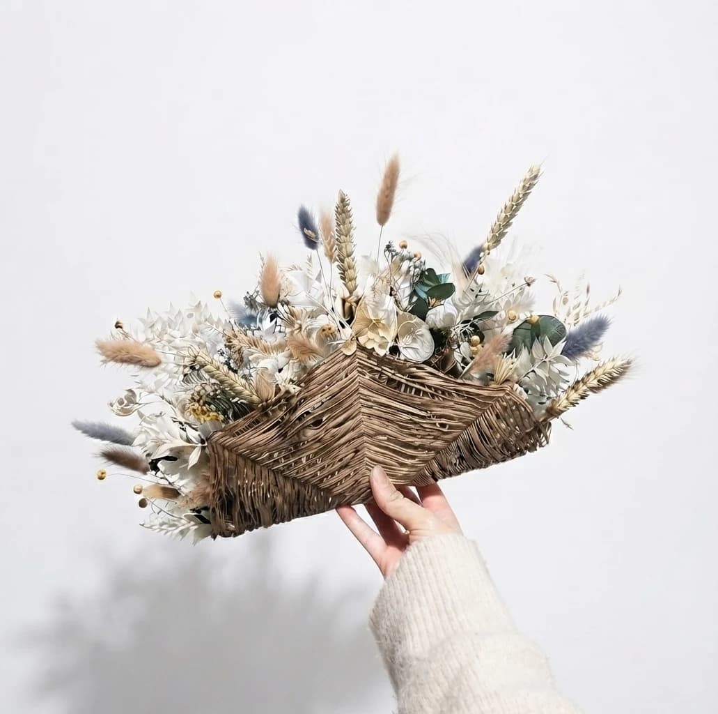 Bouquet de mariée en fleurs séchées blanches et naturelles, composé sur une structure en fibres brunes tressées